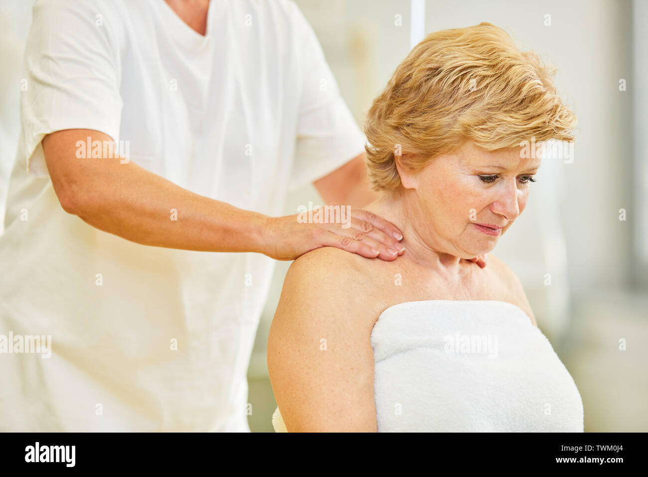 Senior paziente ottiene un massaggio al collo in fisioterapia o chiropratica Foto Stock