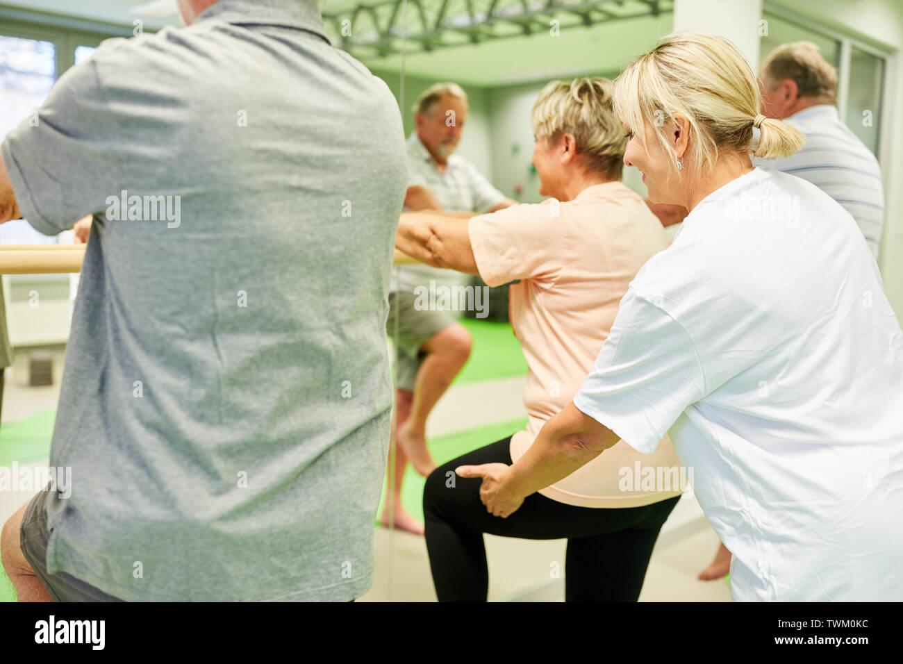 Fisioterapista dà dei cittadini anziani aiutare con la fisioterapia presso il balletto bar Foto Stock