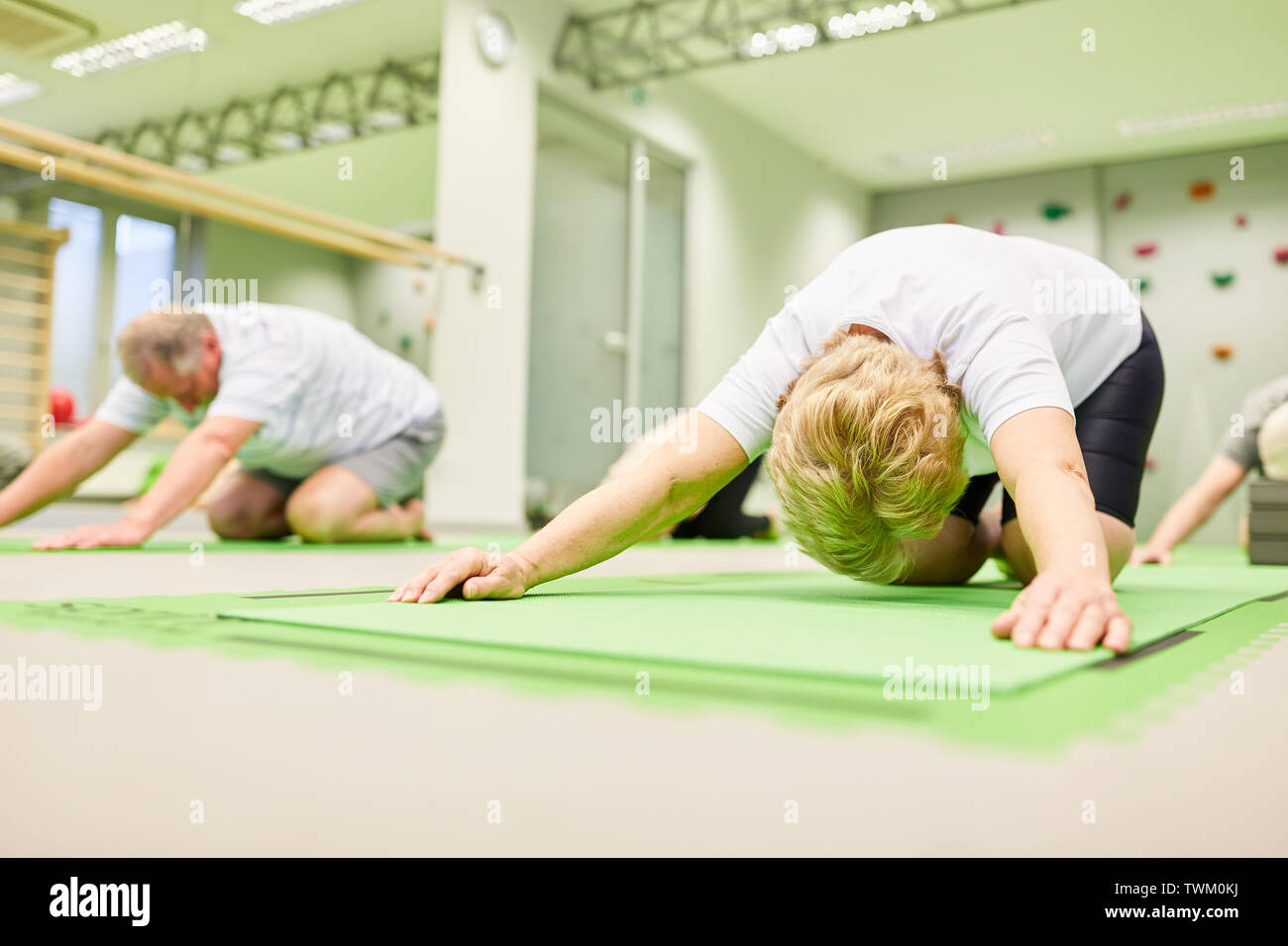 Gli anziani di stiramento e di allungamento in esercizi per la schiena o la fisioterapia Foto Stock