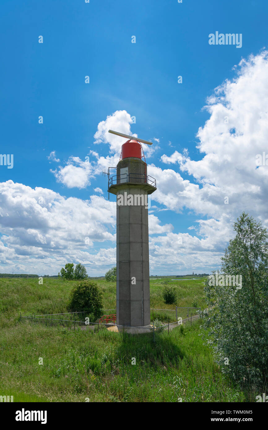Torre del radar in antichi Doel, Belgio con una parte superiore rossa in un ambiente verde e un nuvoloso cielo blu Foto Stock