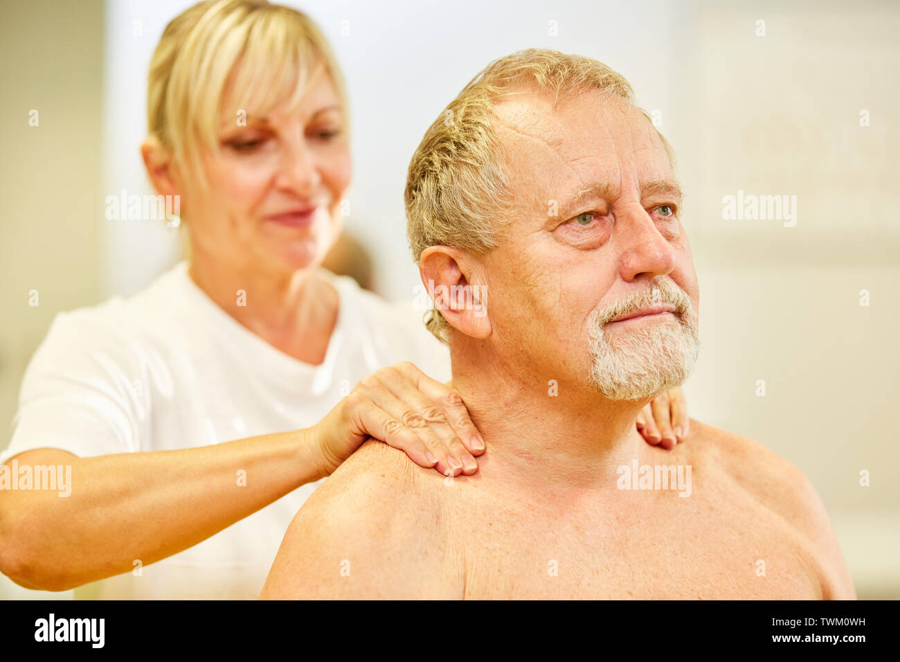 Senior paziente ottiene un massaggio alla schiena o massaggio collo in fisioterapia Foto Stock