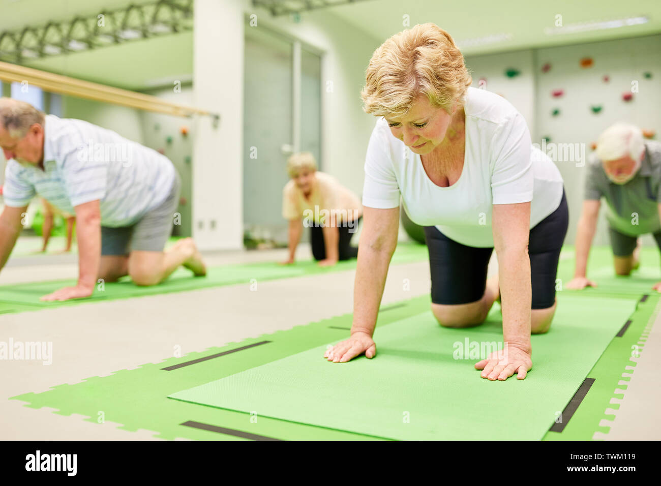 I cittadini anziani fare esercizi per la schiena a sport di riabilitazione in fisioterapia Foto Stock