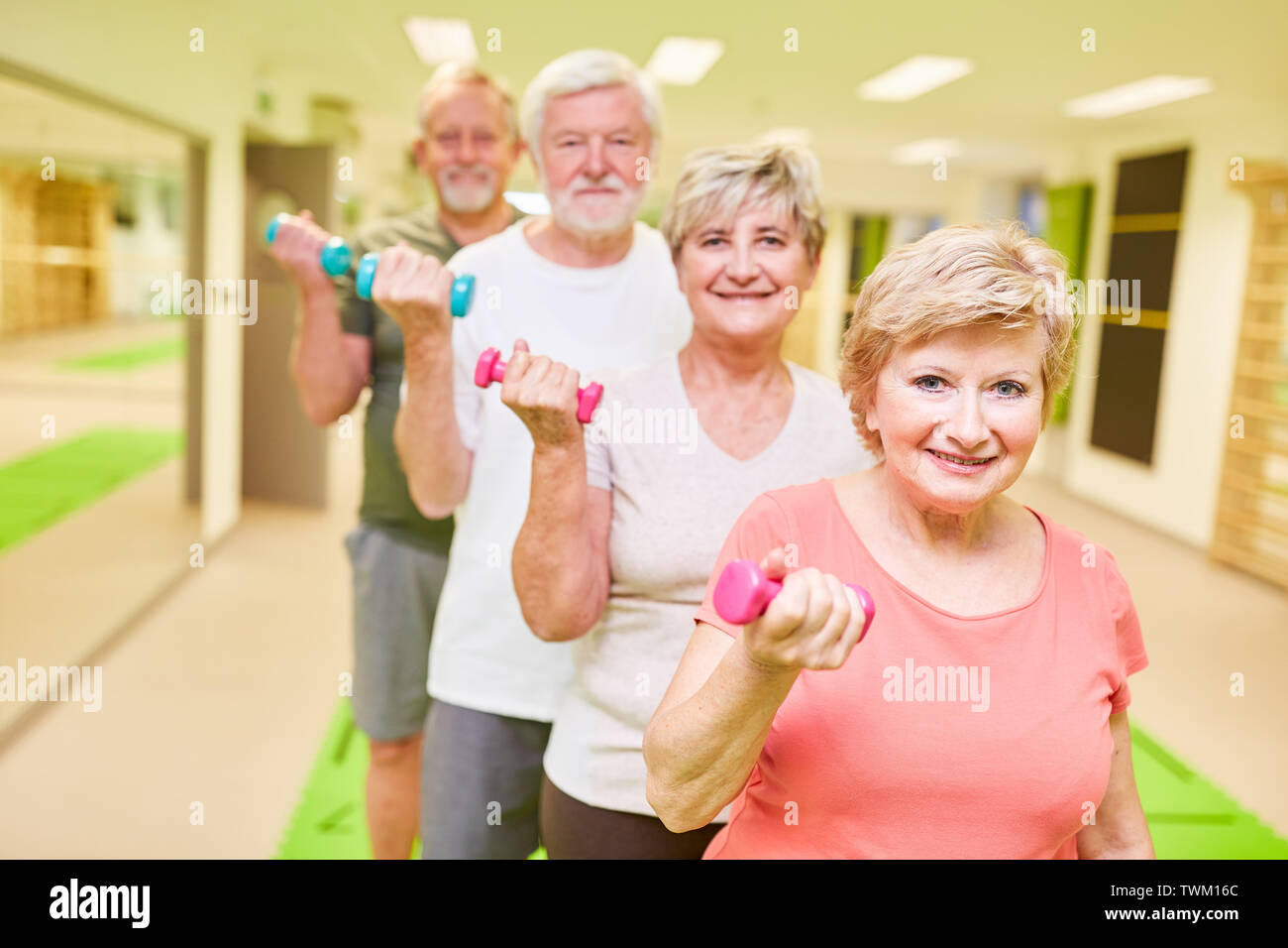 Gruppo di anziani in una lezione di fitness durante l'allenamento con i pesi per costruire il muscolo Foto Stock