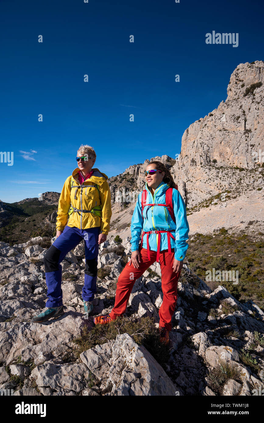 Due donne su una escursione guardando verso la valle, escursionismo in Sierra de Serrella, Quatretondeta-Confrides, provincia di Alicante, Comunidad Valenciana della regione, Foto Stock