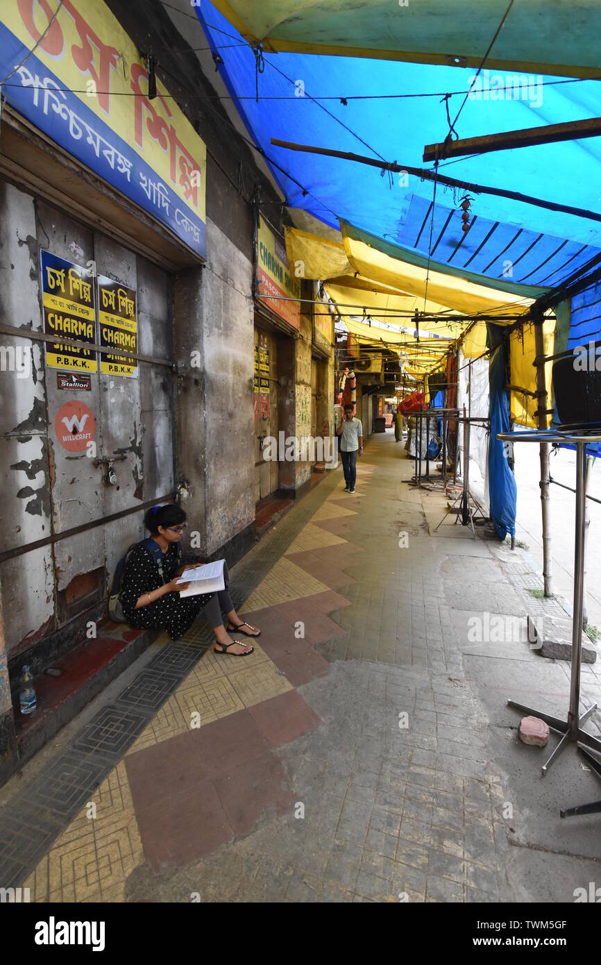 Kolkata, India. 17 Giugno, 2019. Una ragazza sta studiando sul sentiero Gariahat che invadeva da venditori ambulanti vicino a un collegio prima di un esame a Foto Stock