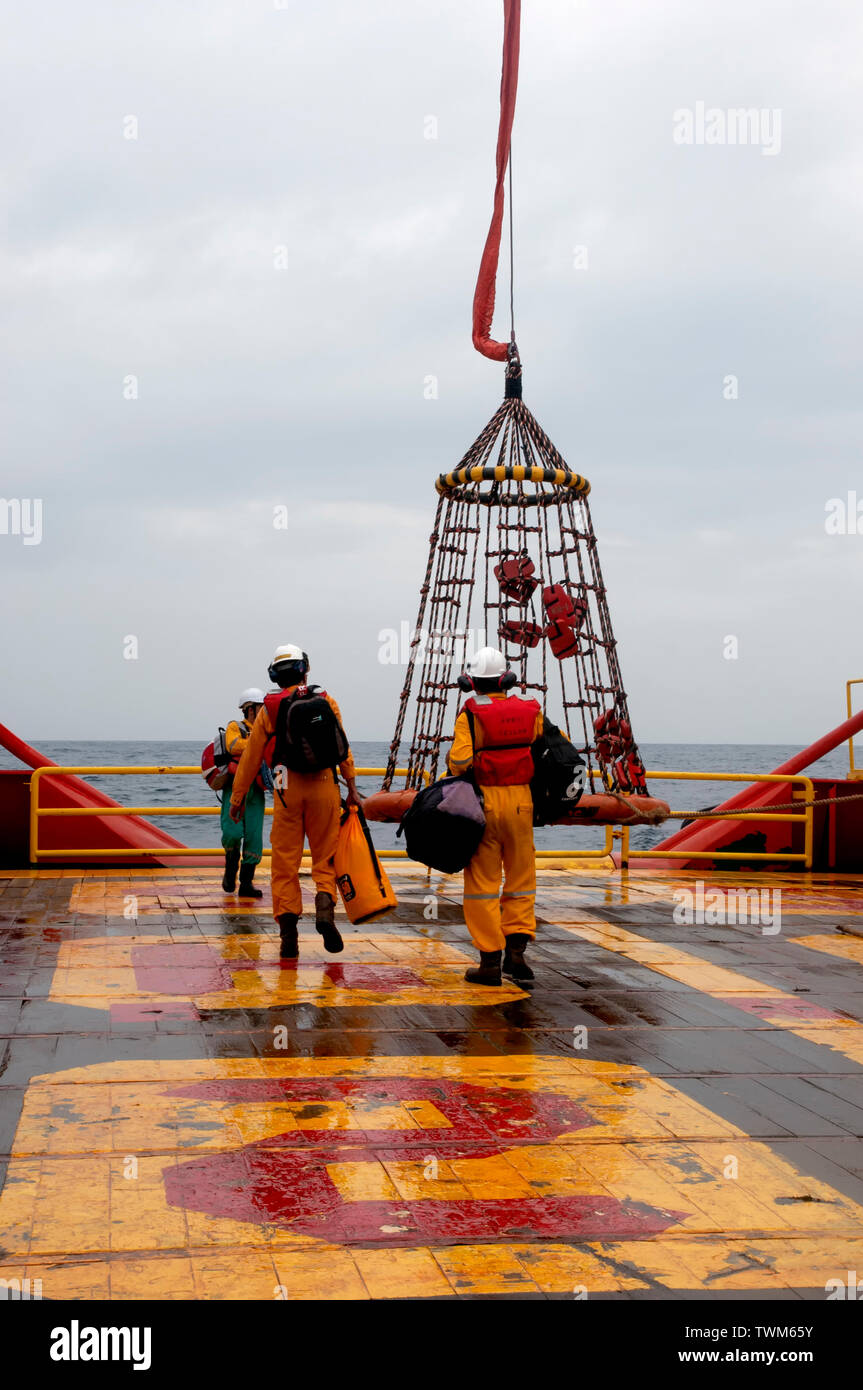 Lavoratore offshore con cesto di sicurezza per imbarco piattaforma di olio Foto Stock