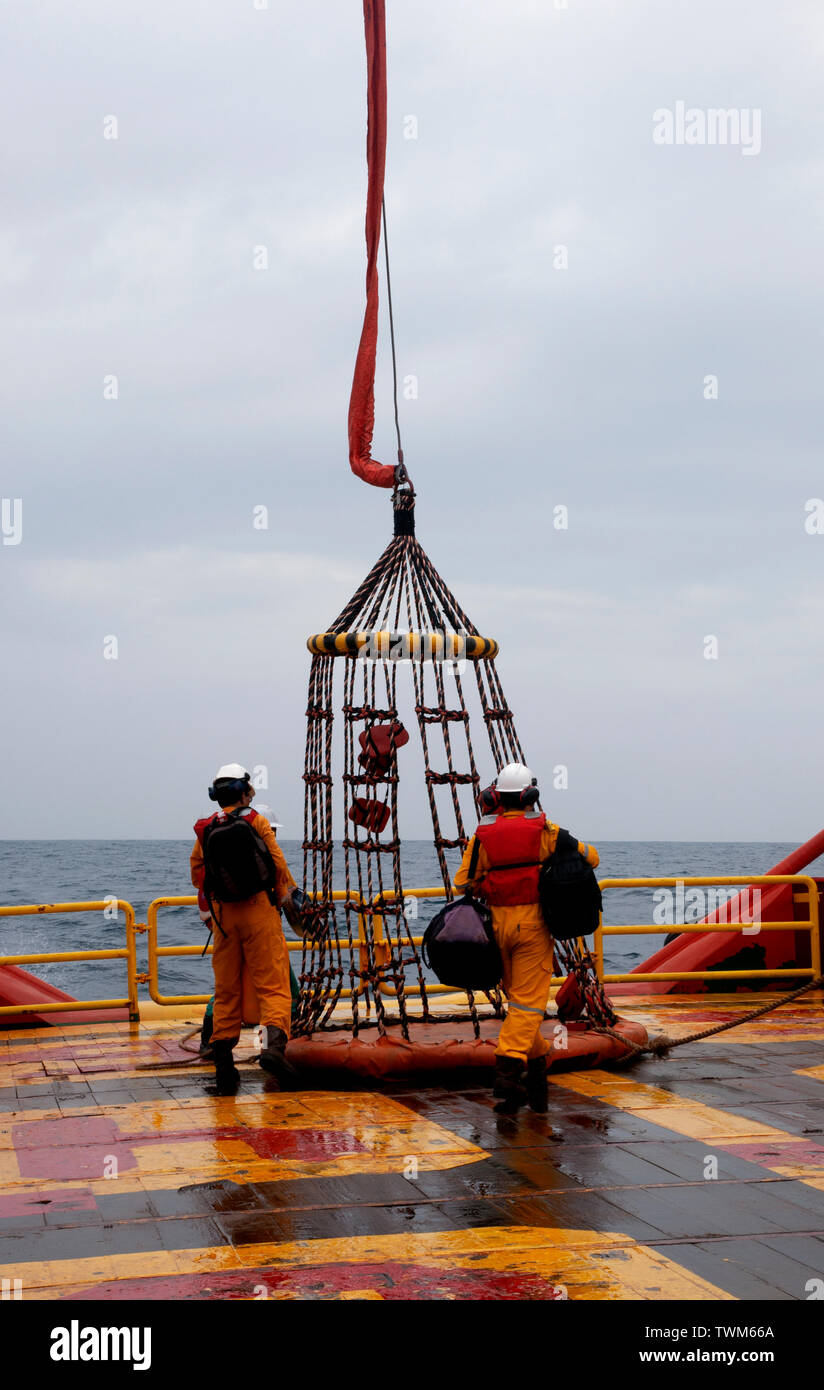 Lavoratore offshore con cesto di sicurezza per imbarco piattaforma di olio Foto Stock