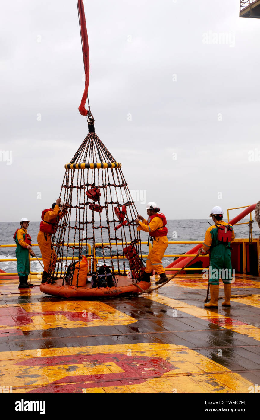 Lavoratore offshore con cesto di sicurezza per imbarco piattaforma di olio Foto Stock