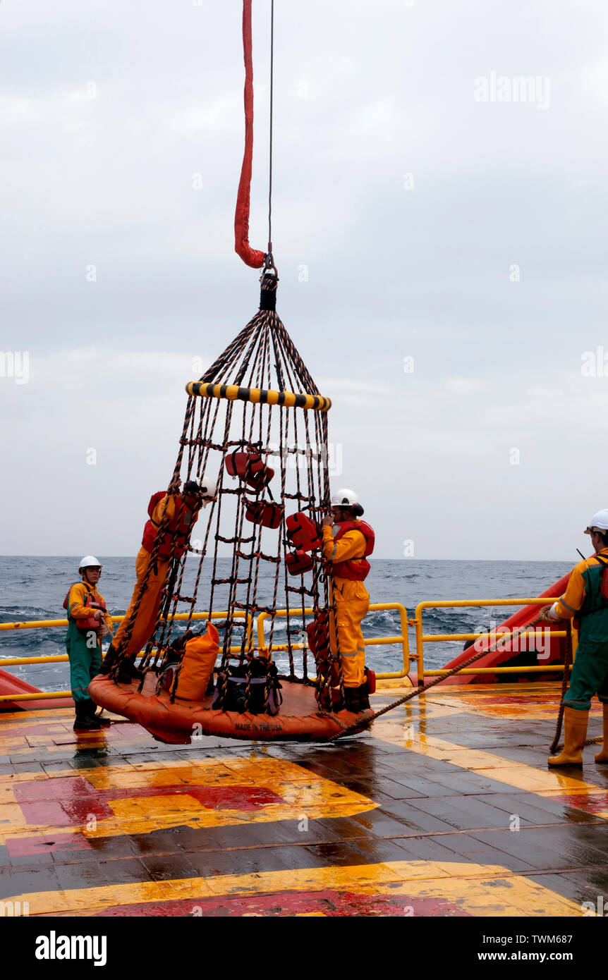 Lavoratore offshore con cesto di sicurezza per imbarco piattaforma di olio Foto Stock