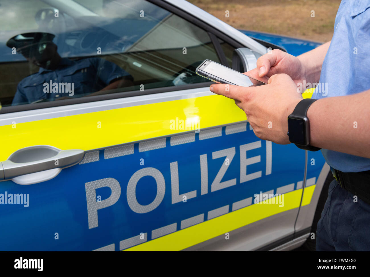 Dresden, Germania. Il 21 giugno, 2019. Un funzionario di polizia sta tenendo il suo smartphone con il nuovo Messenger app, MePol app, nella parte anteriore di una macchina della polizia per le forze di polizia in Sassonia. In una prima fase, 2.300 tali dispositivi mobili del Samsung Galaxy A8 tipo sarà consegnato ai funzionari di polizia da luglio 2019. Gli smartphone sono dotati di speciali programmi, come un messaggero per la cifratura della comunicazione interna, con le app per il documento di controllo, ma anche per la persona e il proprietario del veicolo le indagini. Credito: Robert Michael/dpa-Zentralbild/dpa/Alamy Live News Foto Stock