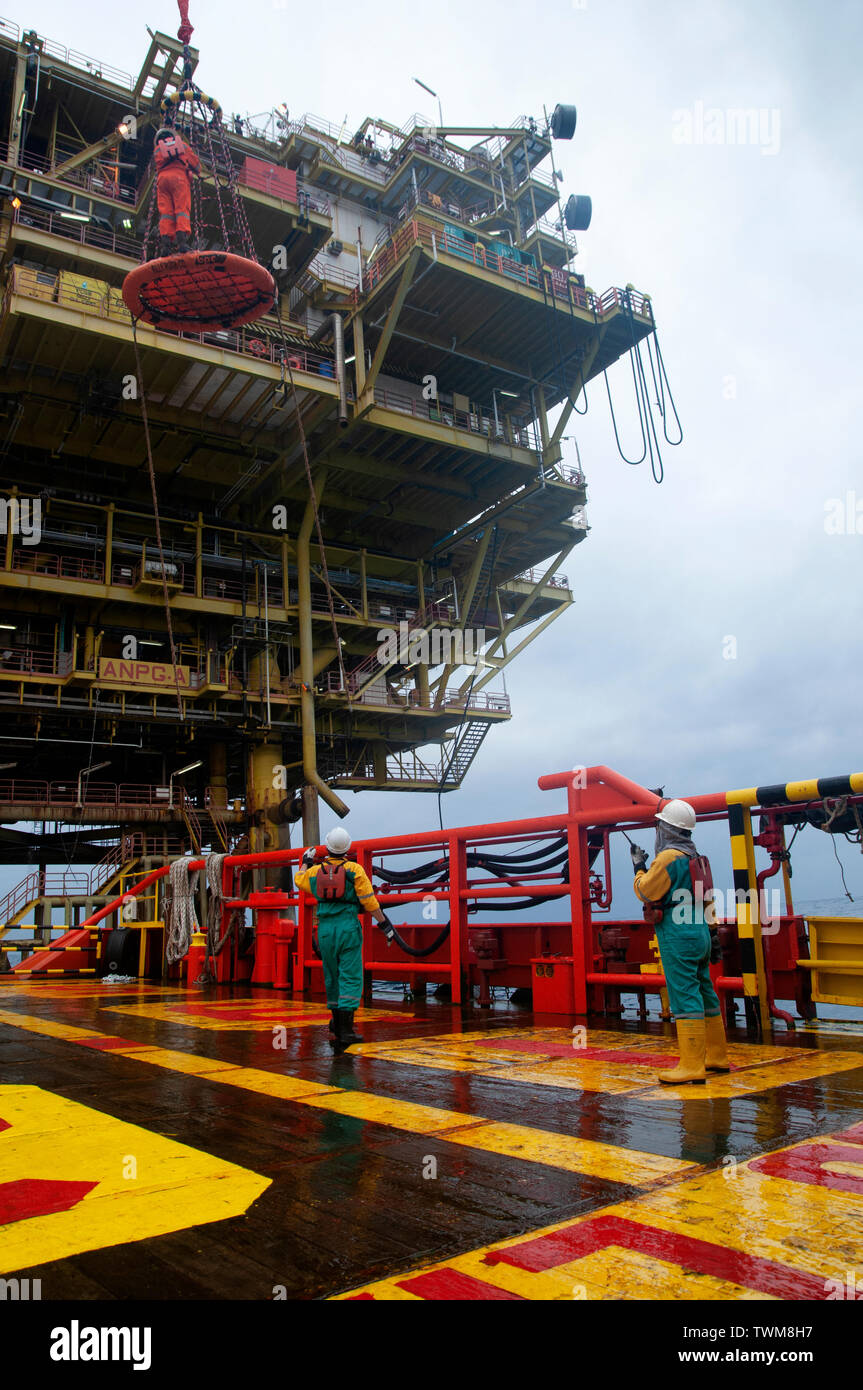 Equipaggio della nave sicuro di sicurezza personale cestello operare dal gruista durante il trasferimento piattaforma petrolifera equipaggio di nave. Foto Stock