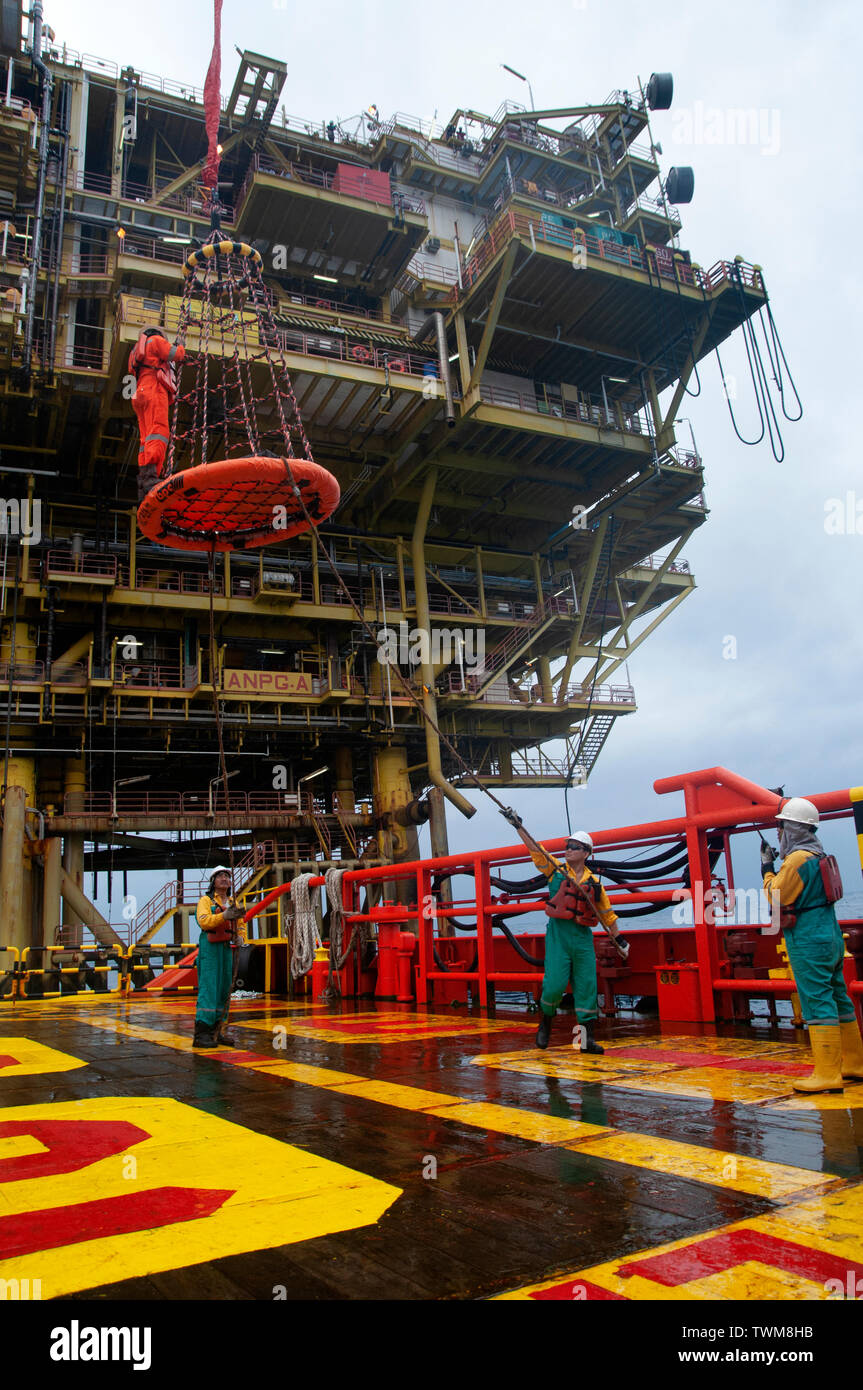 Equipaggio della nave sicuro di sicurezza personale cestello operare dal gruista durante il trasferimento piattaforma petrolifera equipaggio di nave. Foto Stock