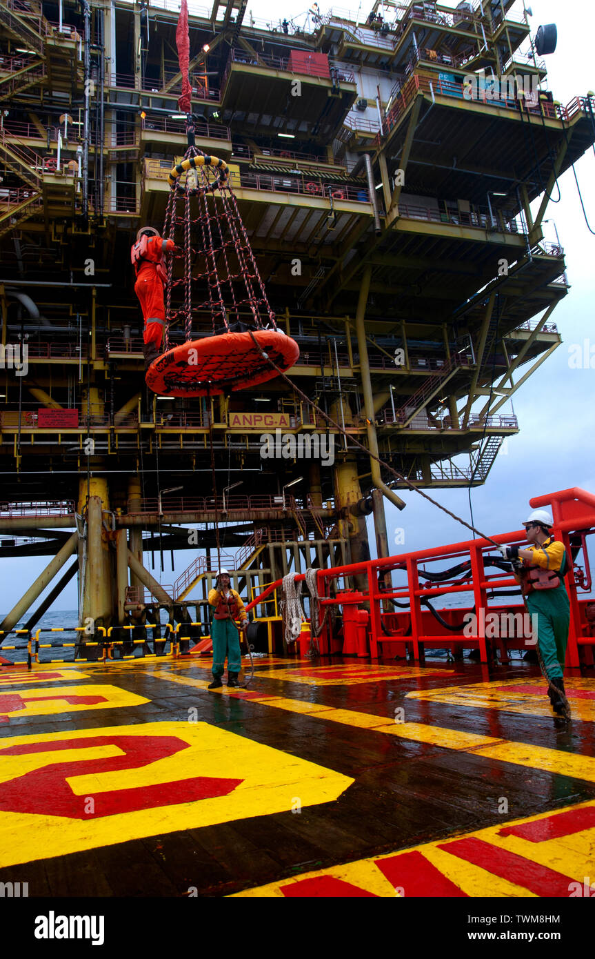 Lavoratore offshore trasferimento dalla piattaforma petrolifera a offshore Nave dal cesto di trasferimento Foto Stock