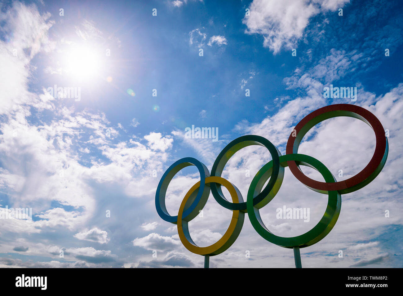 Londra - Aprile 2019: un grande set di anelli olimpici stand retroilluminati da sole luminoso con luce la copertura nuvolosa nel cielo blu. Foto Stock