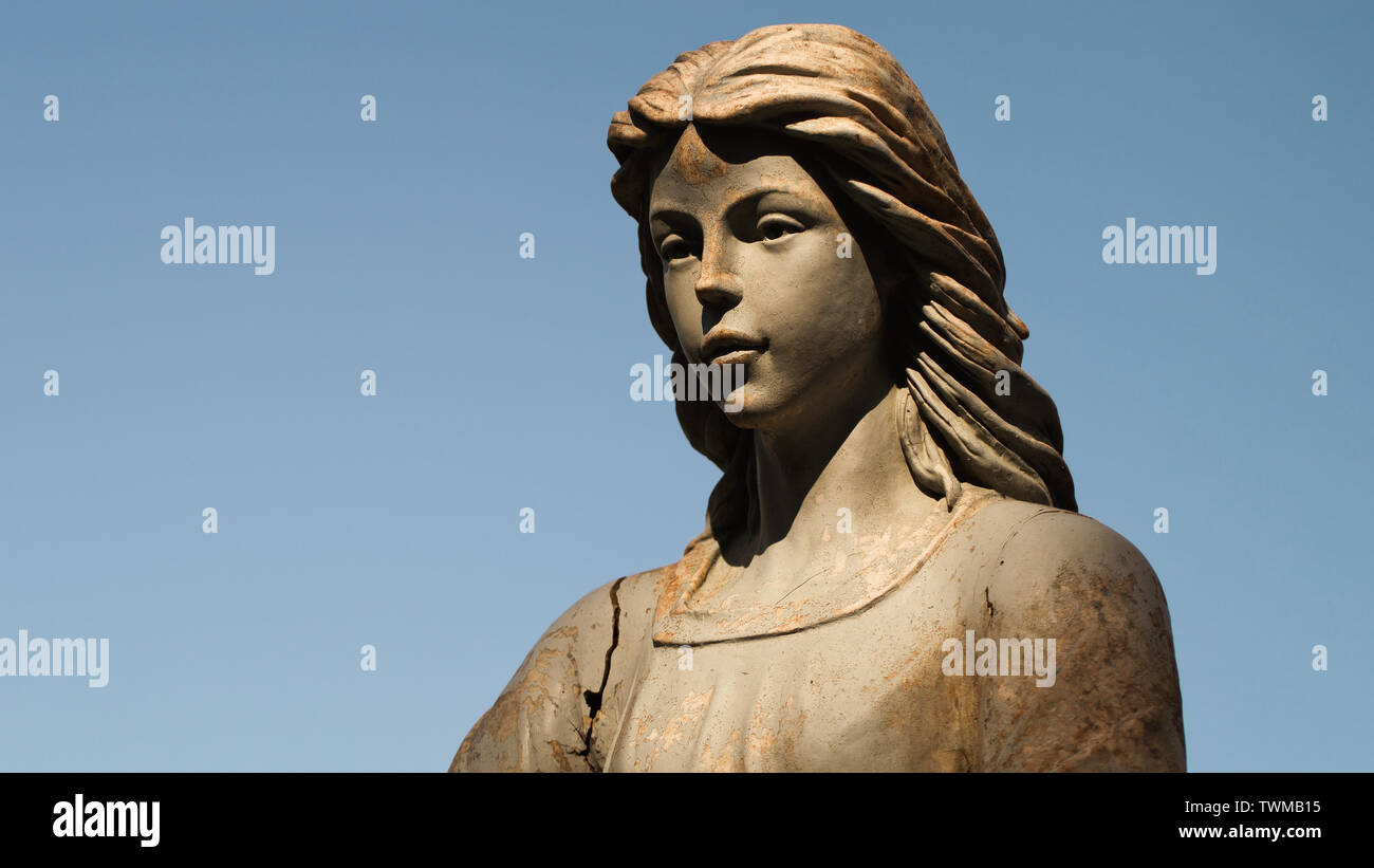 Angelo statua nella luce calda del sole e cielo blu. Foto Stock