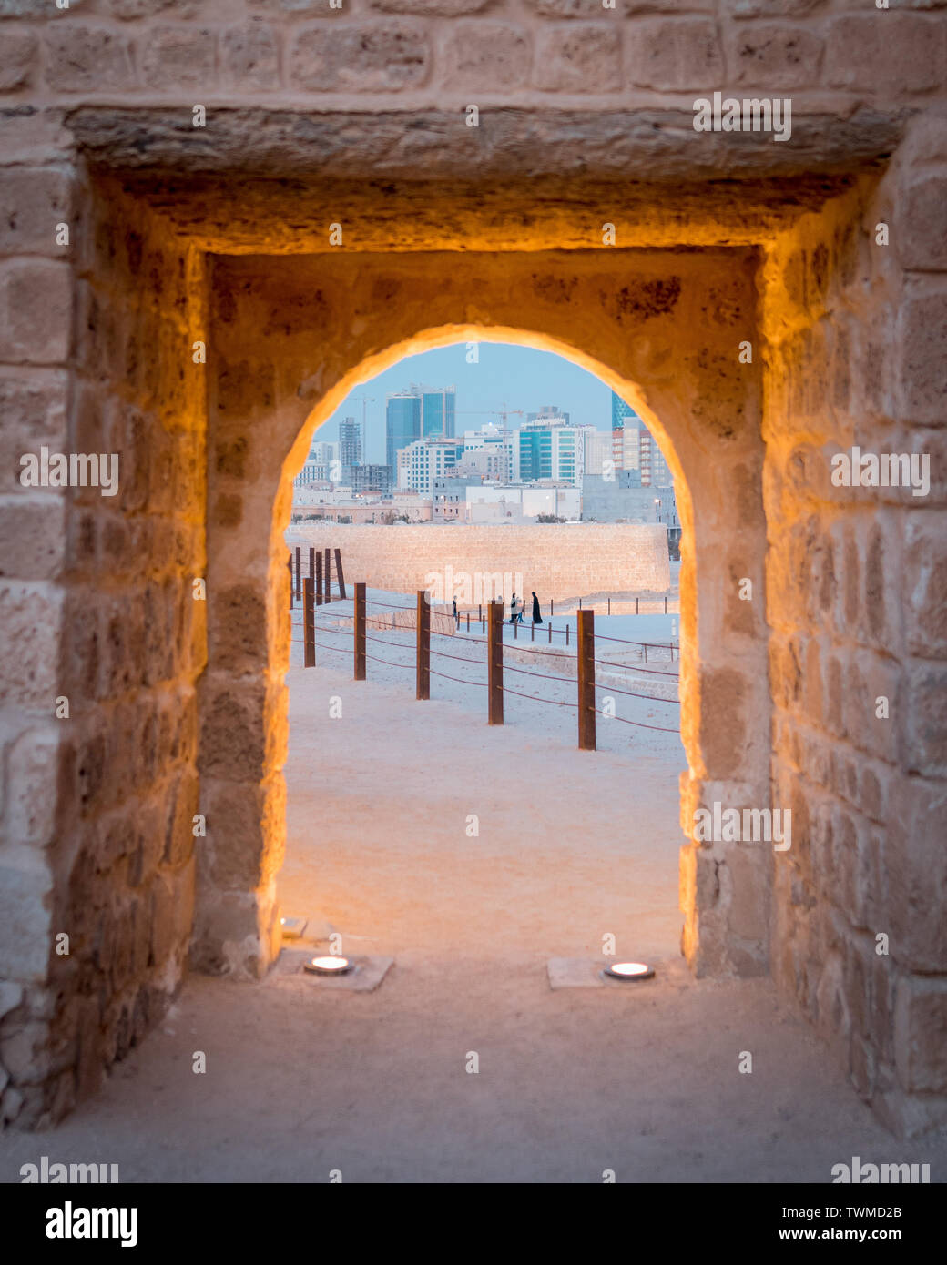 Un castello in pietra il telaio della porta con una vista del Bahrain skyline dove antico incontra il moderno Foto Stock