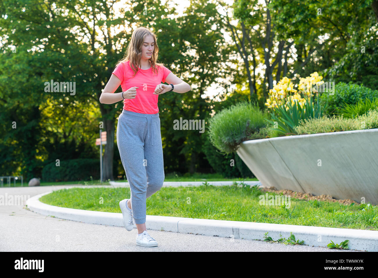 Una giovane donna è in esecuzione nel parco e controlla il suo impulso sul suo orologio fitness Foto Stock