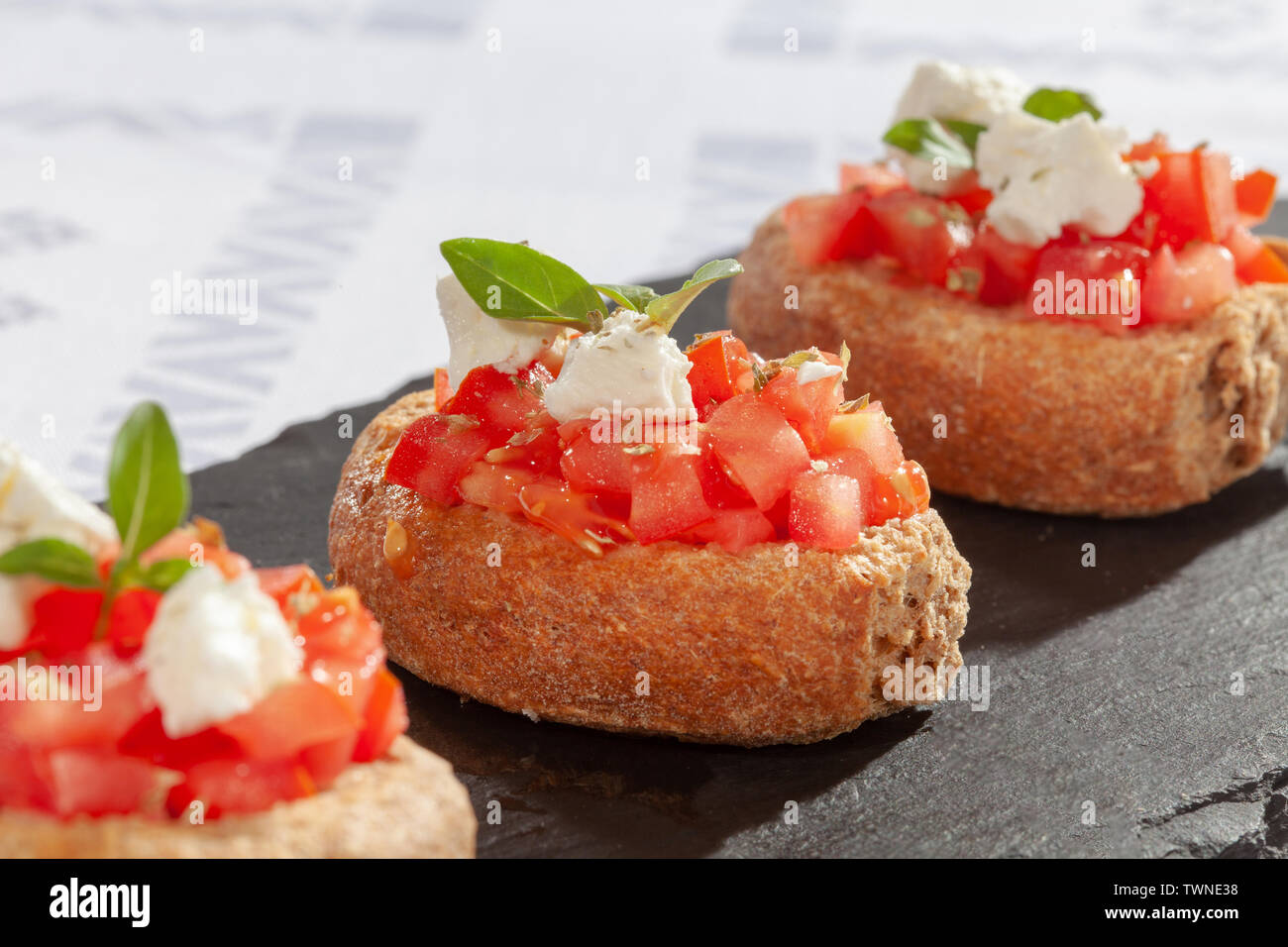 Pane a fette con pezzi tomatoe greco il formaggio feta e foglie verdi per la decorazione Foto Stock