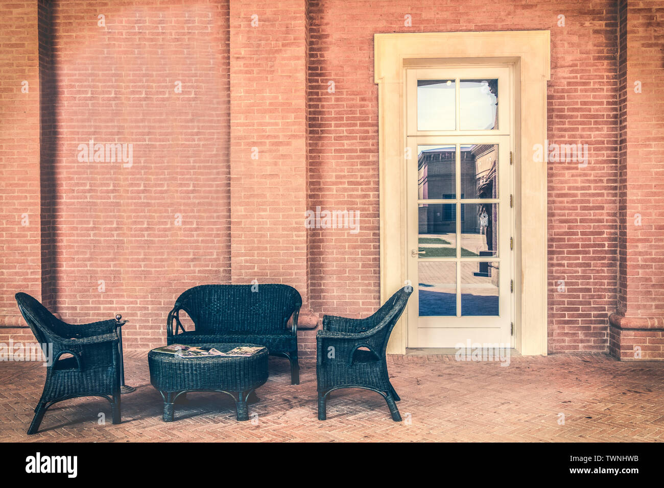 Sala di attesa al di fuori del moderno ed elegante con tavolo riviste poltrone in legno pareti in pietra e porta bianca Foto Stock