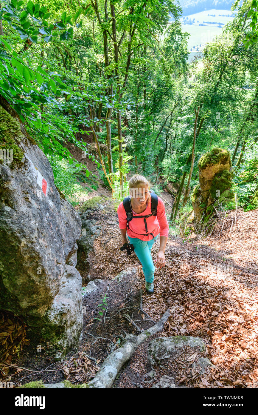 Giovane donna sulla radice impegnativo sentiero nel bosco Foto Stock