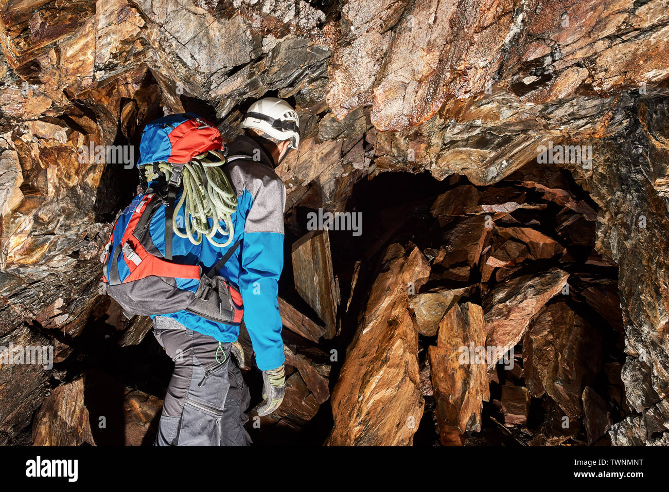 Giovane speleologo esplorando una grotta Foto Stock