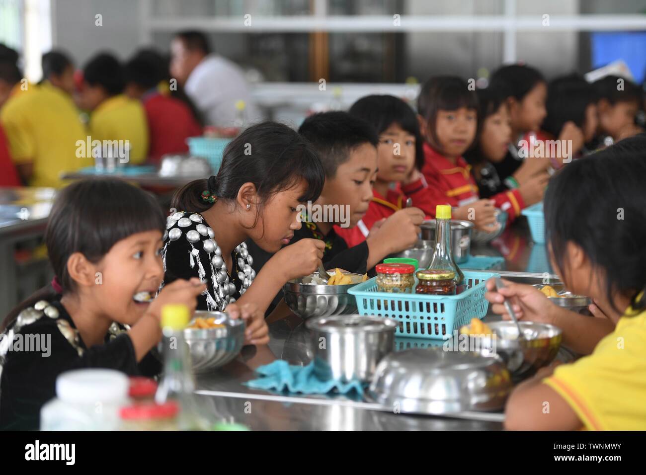 (190622) -- KUNMING, Giugno 22, 2019 (Xinhua) -- Gli allievi hanno il pranzo a Yingpan etnica scuola primaria in Xishan township di Città Mangshi, Dehong dai, e Jingpo prefettura autonoma, a sud-ovest della Cina di Provincia di Yunnan, 21 giugno 2019. Fondata nel 1958, la Yingpan etnica Scuola Primaria dispone di educazione bilingue con mandarin e Jingpo lingua etnica, come 314 dei 369 alunni qui sono di Jingpo gruppo etnico. Un bello e piacevole ambiente di apprendimento è ben fornita per i bambini di diversi gruppi etnici presso la scuola di ereditare le loro culture. (Xinhua/Qin Qing) Foto Stock