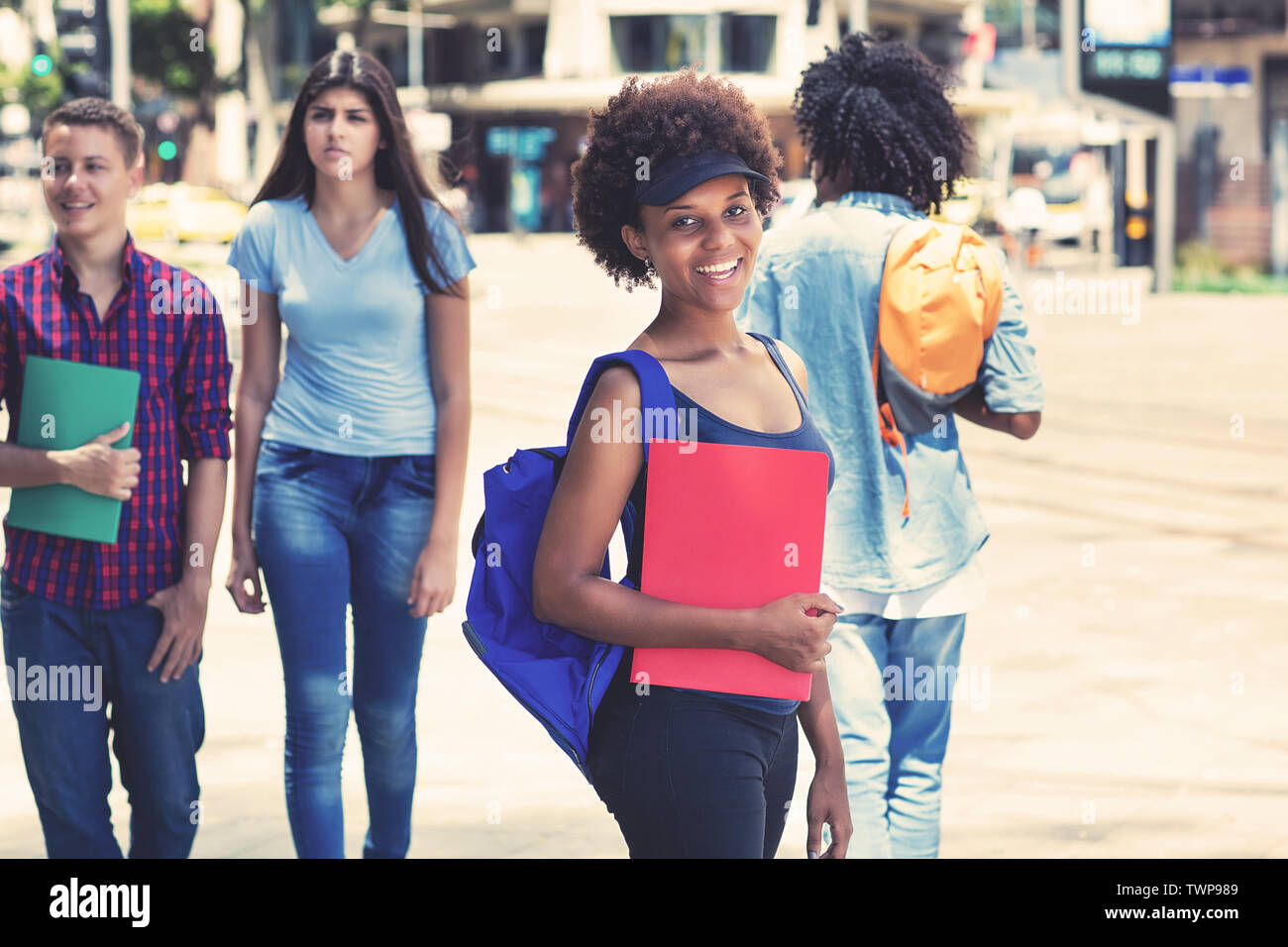 Giovane americano africano studentessa in attesa per bus esterni in città in estate Foto Stock