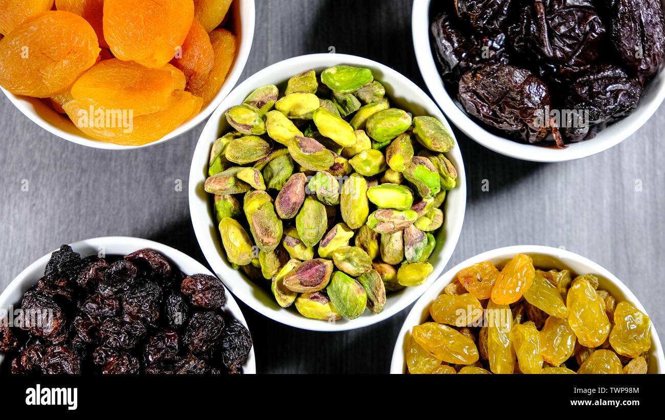 Selezione di una sana frutta e spuntini del dado in bianco bocce guardando verso il basso, i pistacchi, uva sultanina, uva passa, soft albicocche e prugne. Foto Stock