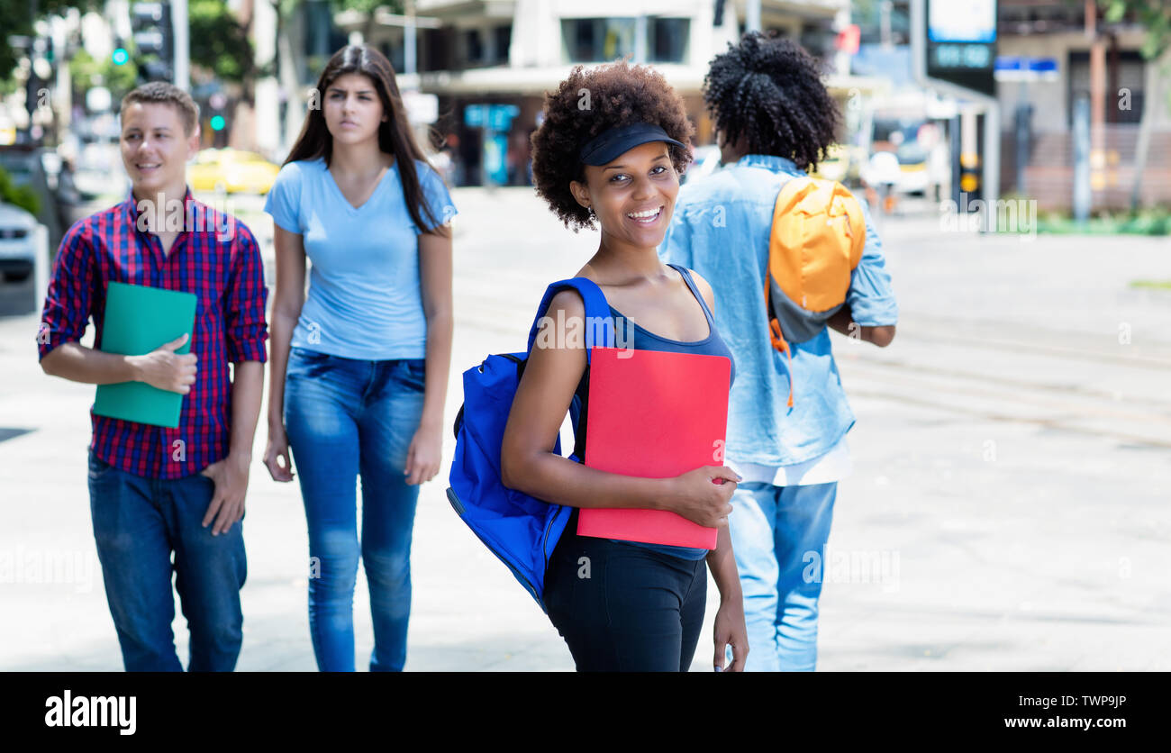 Ridendo African American studentessa in attesa per bus esterni in città in estate Foto Stock