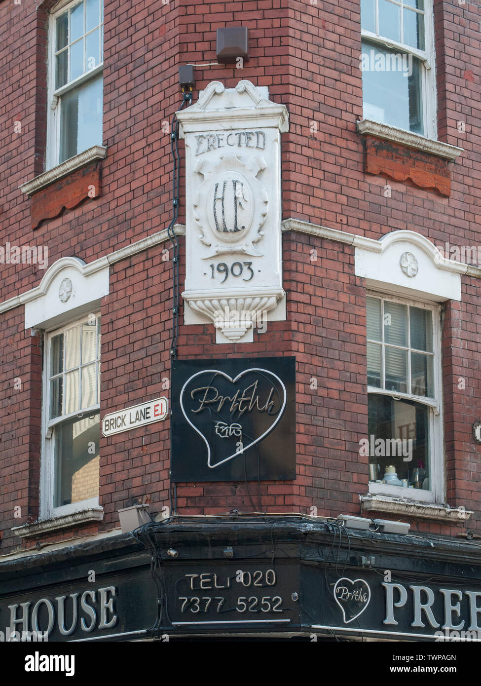 Edificio vittoriano al angolo del Brick Lane e Hanbury Street a Whitechapel che mostra il cartello stradale e la costruzione di età del 1903. Foto Stock