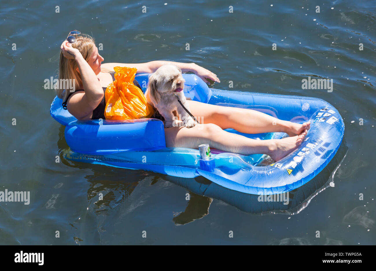 Iford, Dorset, Regno Unito. Il 22 giugno 2019. Il tempo era perfetto, caldo e soleggiato, ancora per Dorset Dinghy giorno con centinaia di gommoni, canotti pneumatici, artigianato, tavole che formano una flottiglia di salpare da ponte Iford giù il fiume Stour a ponte Tuckton. L'evento iniziato nel 2014 come un po' di divertimento, ma ora è diventato un evento annuale la raccolta di fondi per la carità ed il getter più grande di ogni anno. Donna relax nel materasso gonfiabile poltrona gonfiabili con cane. Credito: Carolyn Jenkins/Alamy Live News Foto Stock