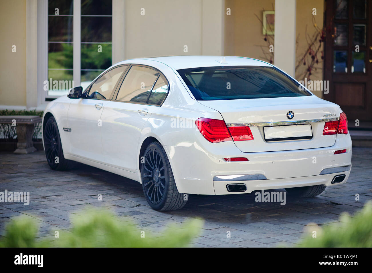 Grodno, Bielorussia, 16 Maggio 2013: il lusso moderno BMW 750Li XDrive auto tre quarti di vista superiore parcheggiato sul lastricato in pietra parcheggio vicino casa antica. Foto Stock