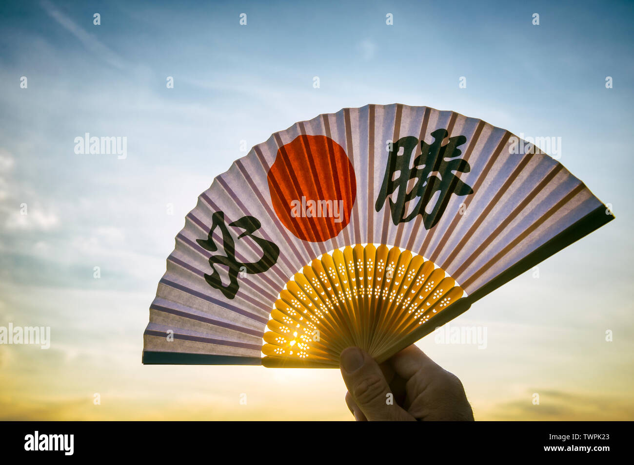 Mano del giapponese sostenitore dello sport tenendo una ventola decorate  con i caratteri kanji compitazione hissho (traduzione inglese: vittoria  certa) di sunrise Foto stock - Alamy
