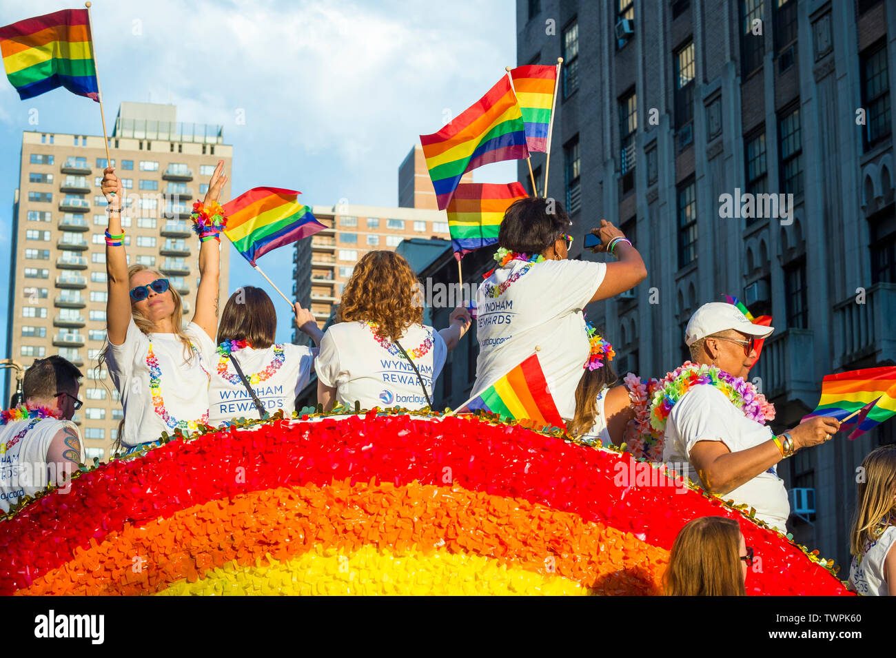 NEW YORK CITY - Giugno 25, 2017: i partecipanti indossano camicie sponsorizzato dalle marche Wyndham e Barclays bandiere d'onda su un galleggiante in Pride Parade. Foto Stock