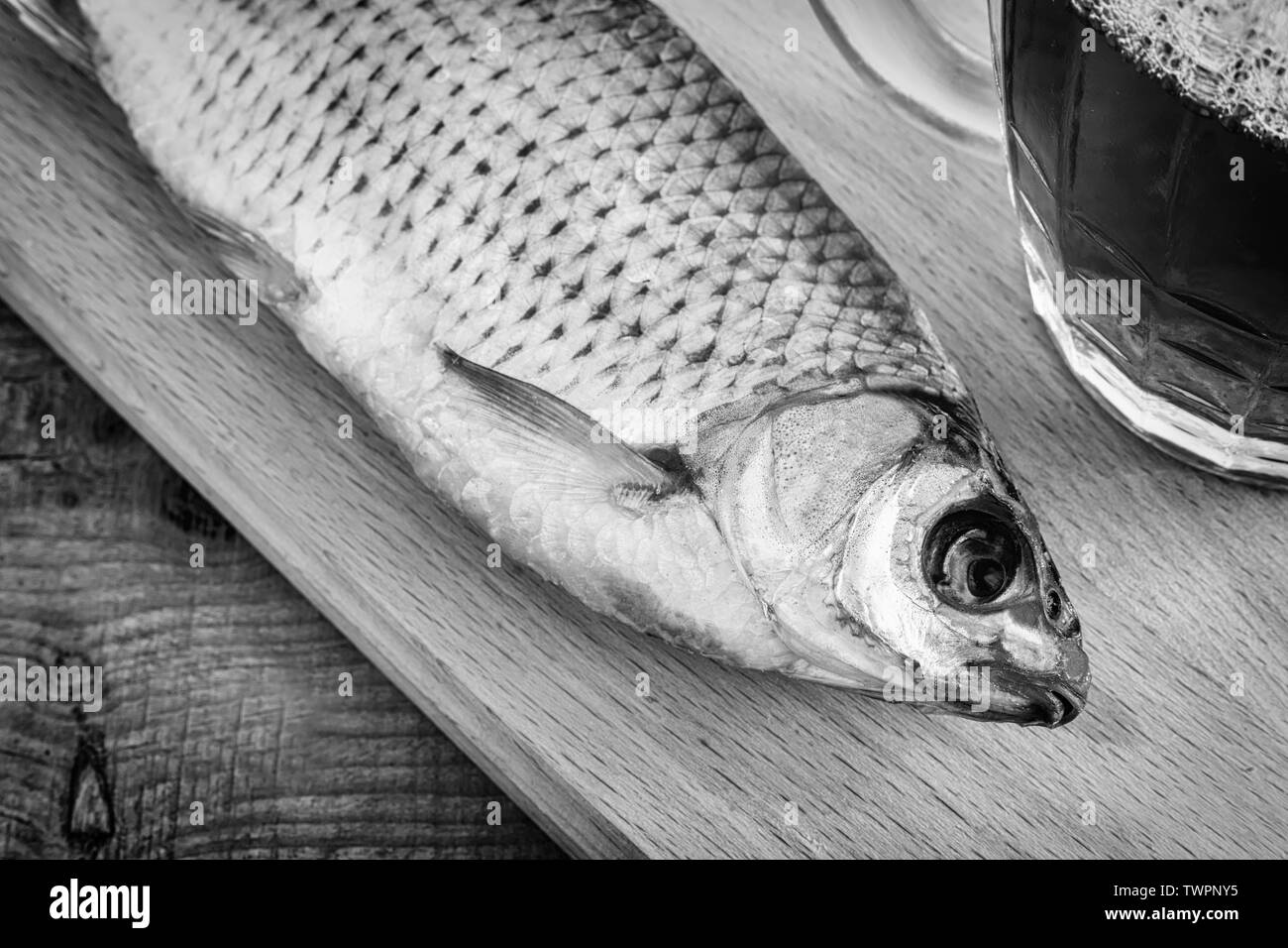 Sul tavolo sul tagliere essiccato roach e la birra in un bicchiere. Presentato close-up. Foto Stock