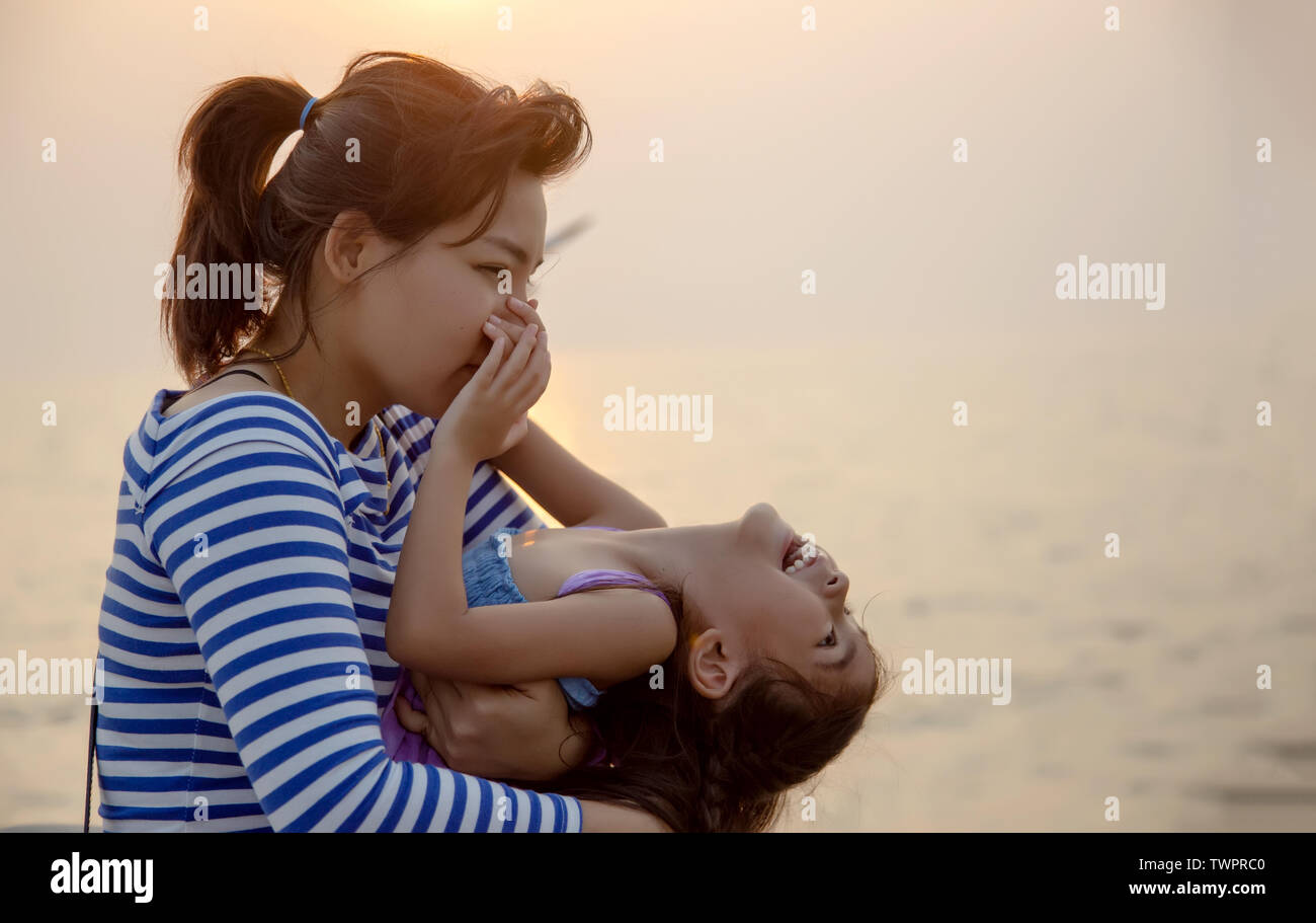 Bel momento con mamma e bambino giocare e abbraccio con il tramonto luce calda. amore insieme famiglia Foto Stock