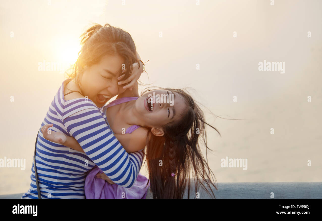 Bel momento con mamma e bambino giocare e abbraccio con il tramonto luce calda. amore insieme famiglia Foto Stock