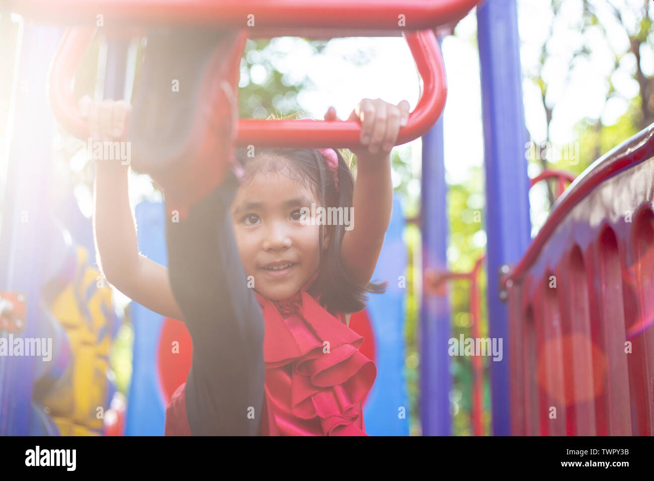 Extreme asian kid giocare appendere gioco all'aperto park la luce del giorno. Foto Stock