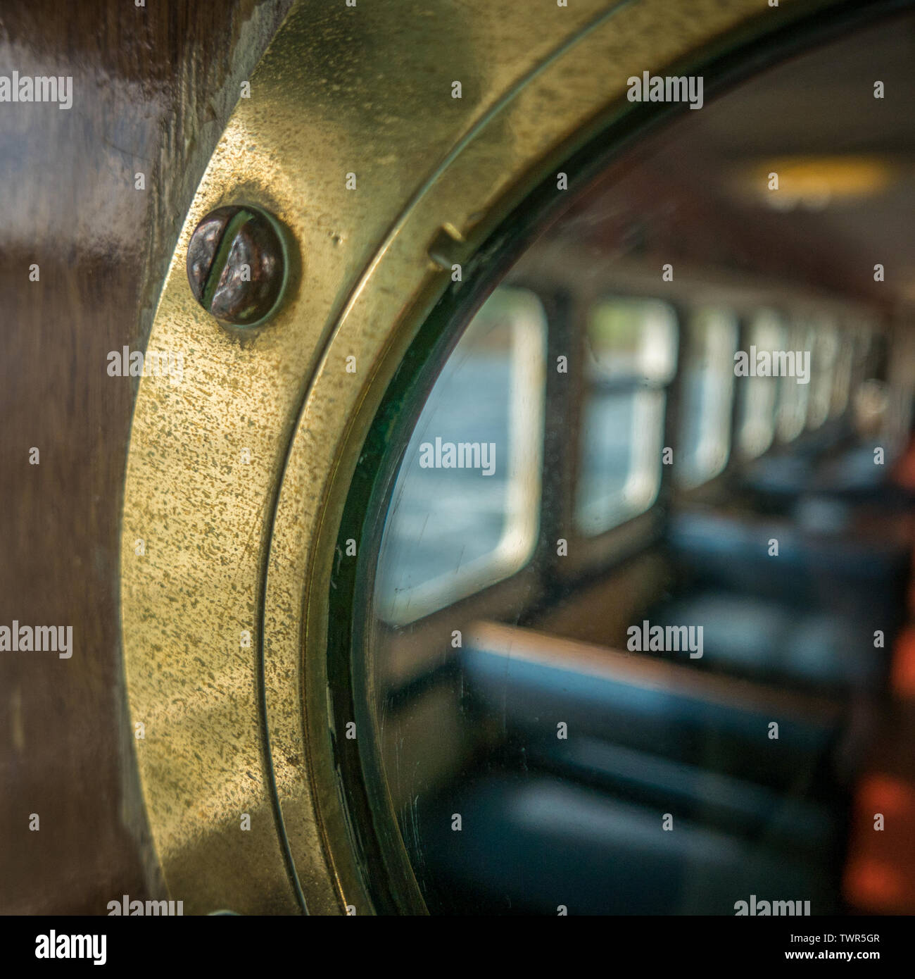 Posti a sedere per passeggeri attraverso un oblò in ottone su una nave o traghetto Foto Stock