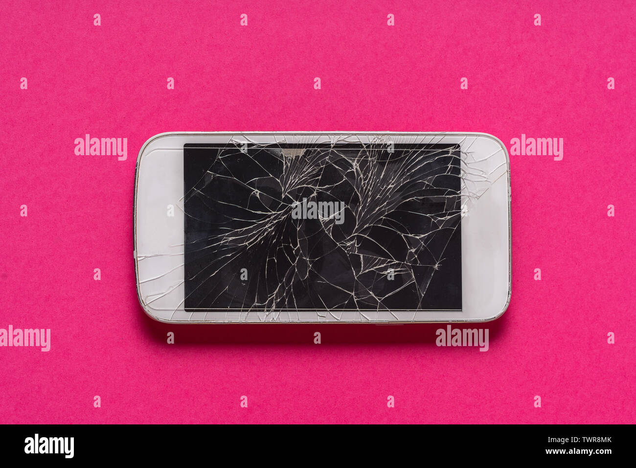 Rotto il telefono cellulare con display rotto su sfondo viola, piatto laici. Foto Stock