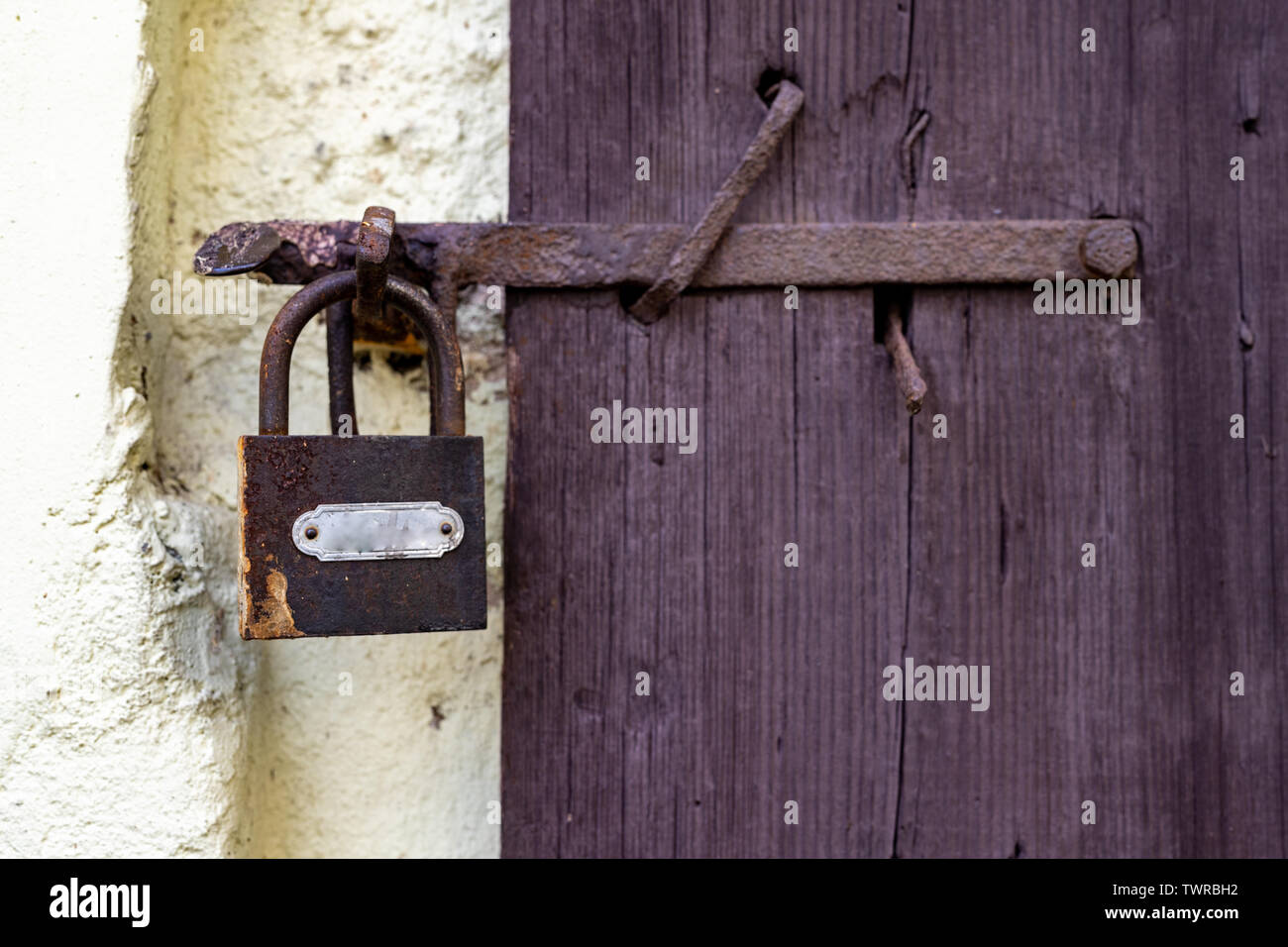 Il vecchio uomo delle salviette da un lucchetto sulla porta dell'edificio rurale. Protezione contro il deterioramento delle antiche porte. Stagione di estate. Foto Stock