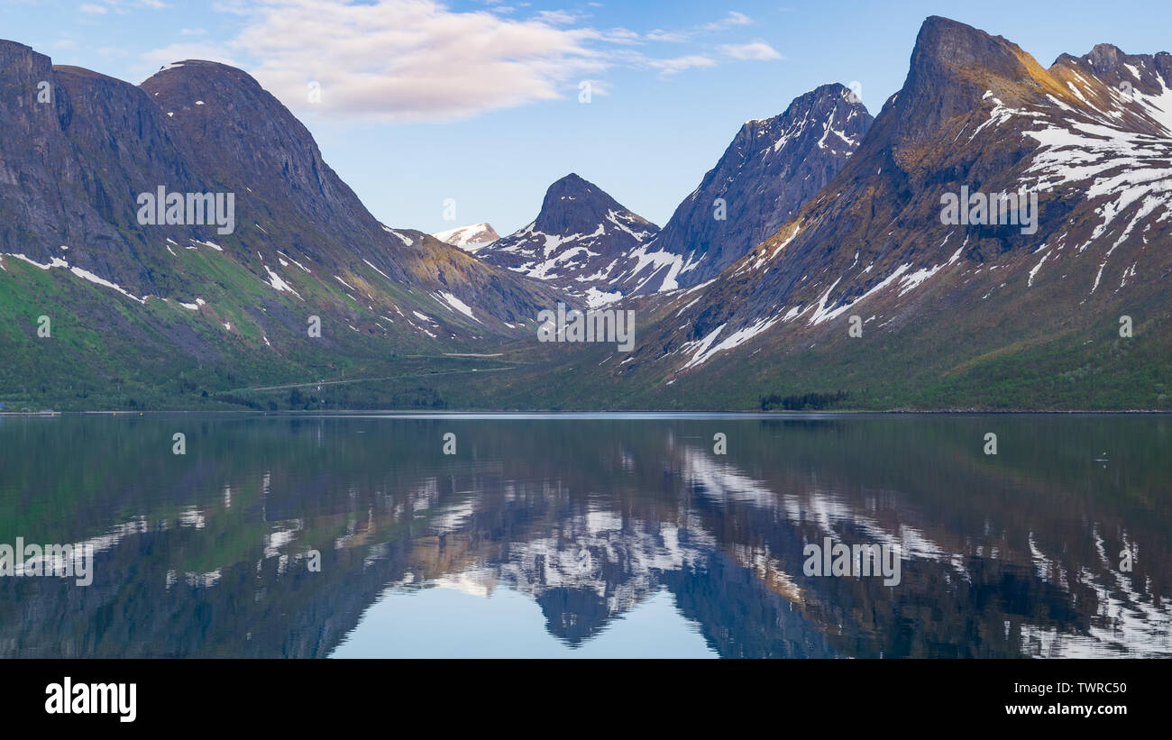 Una bella riflessione di montagna è catturato sul profondo blu acqua di un fiordo appena fuori la Nazionale percorso panoramico sull'artico isola di Senja, Norvegia Foto Stock