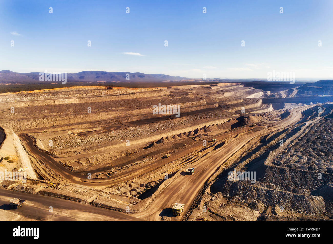 Deep exhavation di combustibili fossili minerali da taglio aperto nero miniera di carbone nella Hunter Valley bacino di carbone di Australia con macchine industriali, camion e e Foto Stock