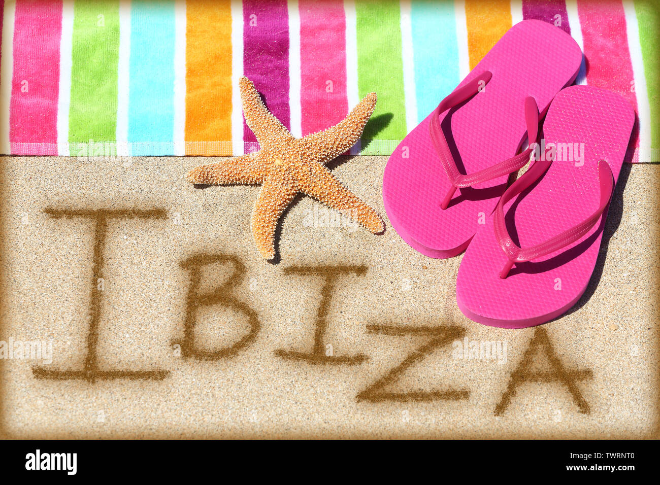 Ibiza beach concetto di viaggio dello sfondo. IBIZA scritto in sabbia con  acqua vicino al telo da spiaggia, estate sandali e stelle marine. Estate e  sole vacanze vacanze sulle isole Baleari, Spagna