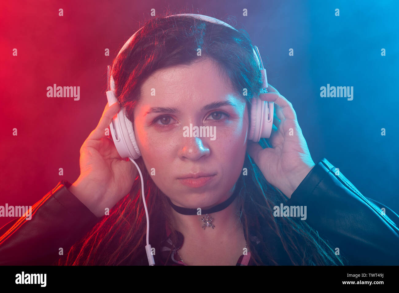 Godetevi, meloman e concetto di persone - una giovane donna con dreadlocks ascoltando la musica, ritratto su sfondo scuro Foto Stock