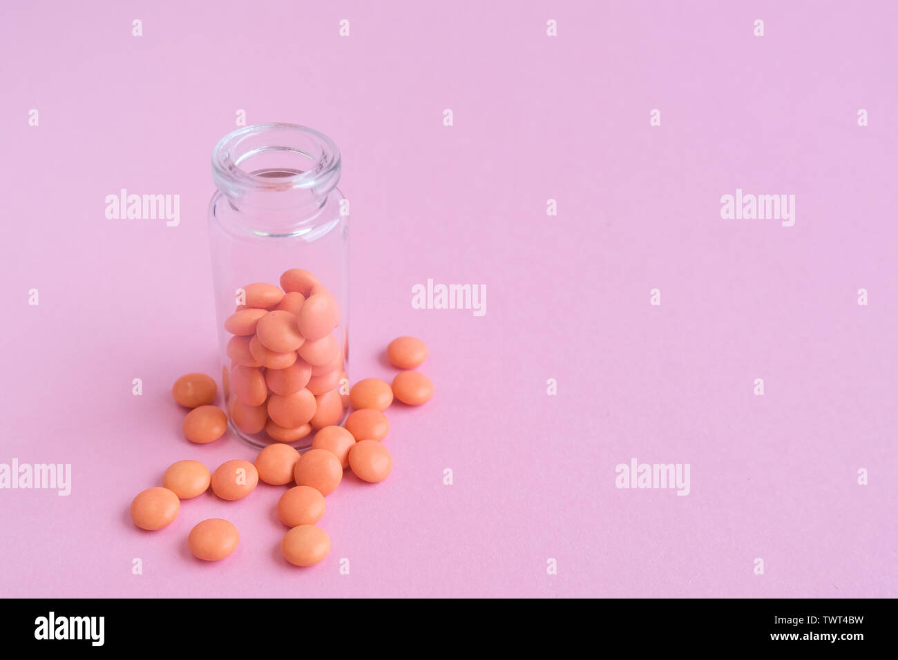 Le compresse di colore arancione dalla bottiglia di vetro su sfondo rosa. copyspace per il testo. Epidemia, antidolorifici, healthcare, trattamento pillole e abuso di droga concetto. Foto Stock