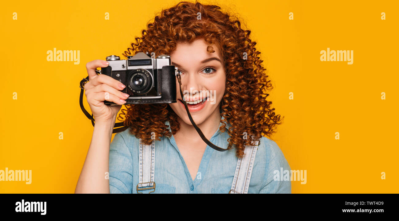 Hey sorriso si sono stati fotografati. Positivo dai capelli ricci teenager fare una foto su sfondo giallo. Foto Stock