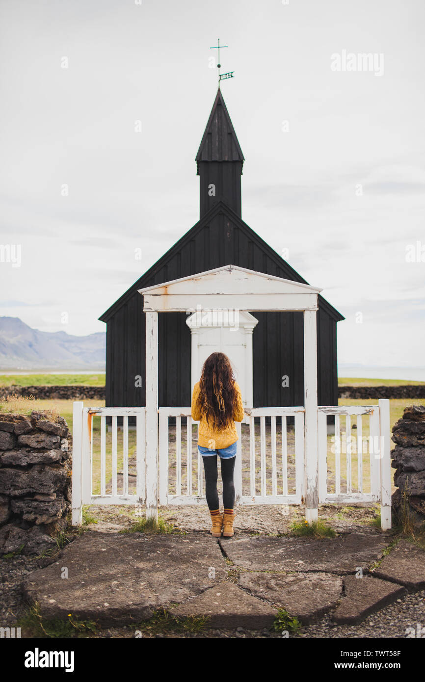 Donna che guarda sulla famosa chiesa nera di Budir alla penisola Snaefellsnes regione in Islanda. Benvenuti in Islanda. Sguardo d'autunno. Foto Stock