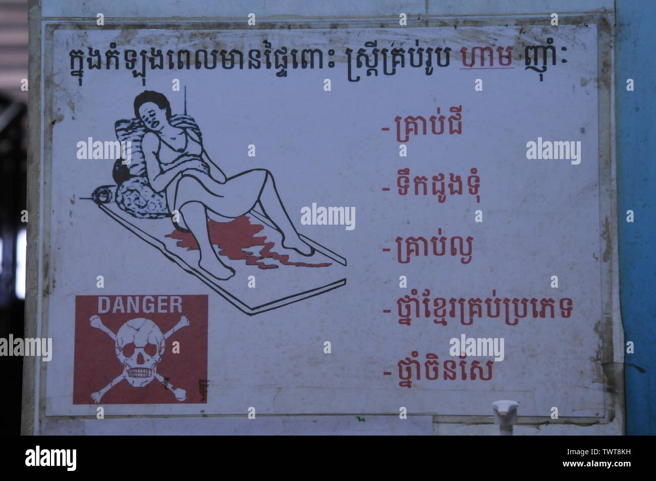 I pericoli del parto. Segnale di pericolo bilingue sul parto in un ospedale di maternità, Phnom Penh, Cambogia. Crediti: Kraig Lieb Foto Stock