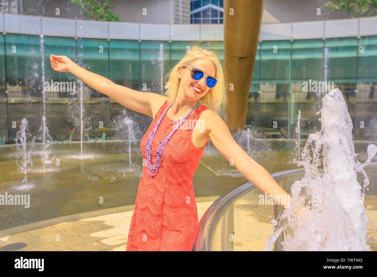 Fontana della Ricchezza a Suntec Tower, la più grande fontana in Singapore. Lifestyle tourist toccando l'acqua della fontana per una migliore fortuna. Blonde caucasian Foto Stock